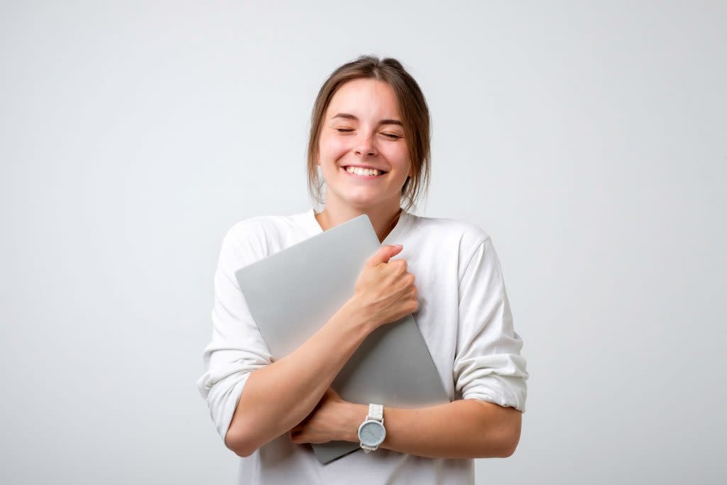 A woman hugs a laptop.