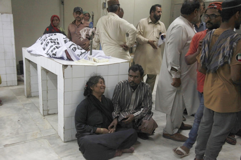 A woman mourns as other gather next to body of the victim of stampede, at a morgue, in Karachi, Pakistan, Friday, March 31, 2023. Several people were killed in the deadly stampede at a Ramadan food distribution center outside a factory in Pakistan's southern port city of Karachi, police and rescue officials said. (AP Photo/Ikram Suri)