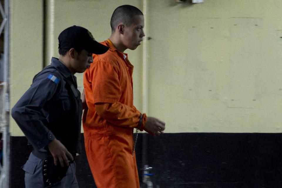 A police agent escorts Mexican national Jose Daniel Castillo to a courtroom in Guatemala City, Friday, Feb. 21, 2014. Castillo and eight other alleged members of Los Zetas drug cartel were each sentenced to 106 years in prison, after they were found guilty of participating in the May 14, 2011 massacre of 27 farm laborers in Peten, north of Guatemala City. (AP Photo/Moises Castillo)
