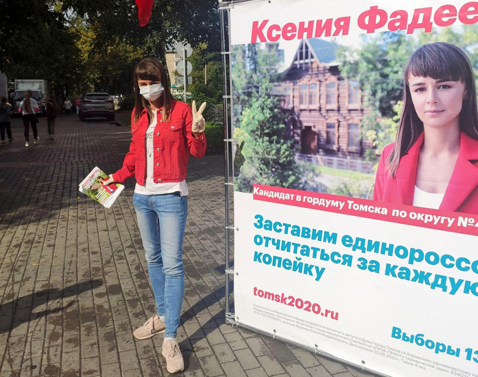 In this August 2020 photo provided by Alexei Navalny's team, Ksenia Fadeyeva, who is running for the city council in Tomsk, Russia, poses for a photo next to her election poster. Fadeyeva has secured a seat in the city council, according to preliminary results of the regional election that took place on Sunday, Sept. 13, 2020. (Andrei Fateyev/Alexei Navalny's team via AP)