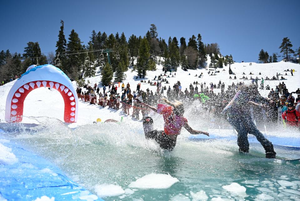 A participant crashes into the pond during the pond skim contest at Bear Mountain Resort for the Bear Break event on Saturday, April 6, 2024 in Big Bear.