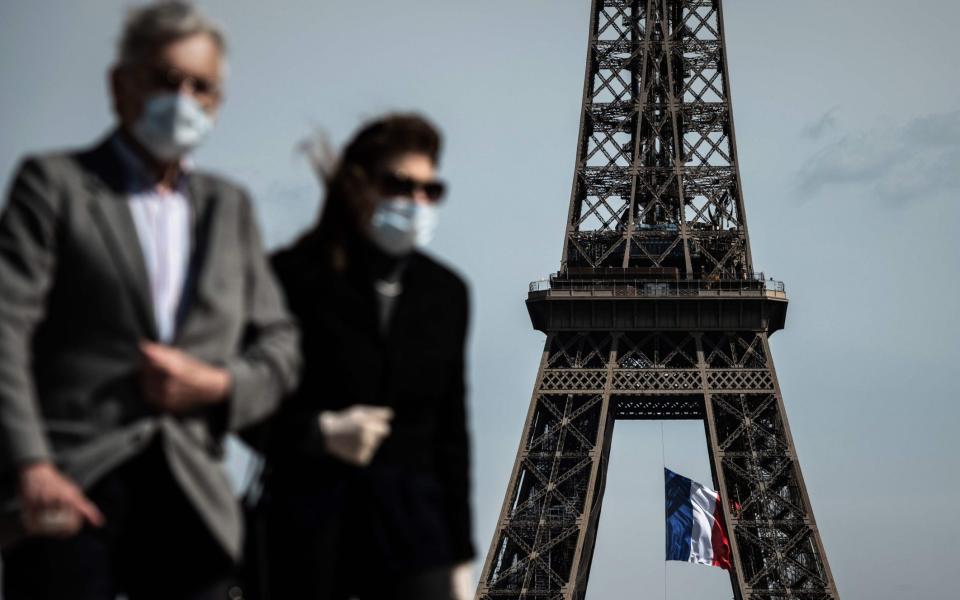 FILES) In this file photo taken on May 11, 2020, a man and a woman wearing face masks walk on Trocadero Plaza as a French national flag flies on the Eiffel Tower in background in Paris on the first day of France's easing of lockdown measures in place for 55 days to curb the spread of the COVID-19 pandemic, caused by the novel coronavirus. - Wearing a mask will be compulsory in parts of Paris and its wider region from August 10, 2020, to combat a rise in coronavirus infections in and around the French capital, the police said. The mask will be obligatory for all those aged 11 and over from 8:00 am (0600 GMT) on August 10 "in certain very crowded zones", the police said in a statement on August 8, without yet detailing which areas were affected. - PHILIPPE LOPEZ/AFP via Getty Images