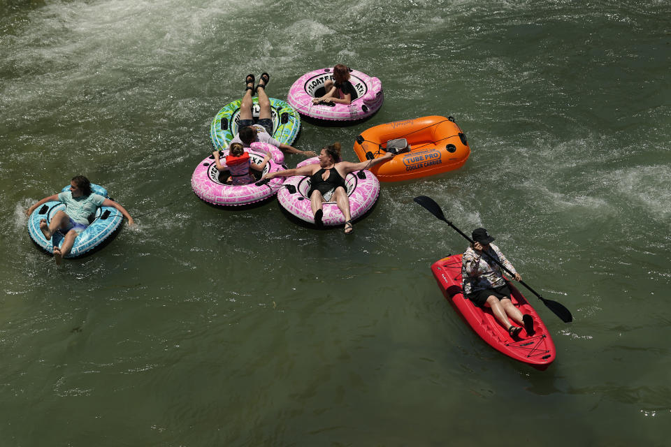 A kayaker and tubers float the cool Comal River in New Braunfels, Texas, Thursday, June 29, 2023. Meteorologists say scorching temperatures brought on by a heat dome have taxed the Texas power grid and threaten to bring record highs to the state. (AP Photo/Eric Gay)