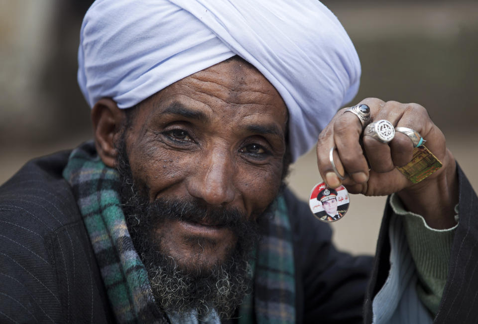 FILE - In this Tuesday, Jan. 14, 2014 file photo, an Egyptian man holds a pin with a picture of Egypt's Defense Minister, Gen. Abdel-Fattah el-Sissi as he waits for his turn to cast his vote in the country's constitutional referendum in Cairo, Egypt. Having secured victory in a referendum on a relatively liberal constitution that he championed, insiders say Egypt's military chief is turning his attention to the country’s overwhelming array of problems _ from health and education to government subsidies and investment. The revelations offer the latest indication that Gen. Abdel-Fattah el-Sissi is planning a run for president, capping a stunning transformation for the 59-year-old who started in the infantry.(AP Photo/Khalil Hamra, File)