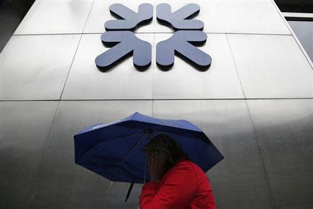 A woman shelters under an umbrella as she walks past a branch of the Royal Bank of Scotland in the City of London September 17, 2013. REUTERS/Stefan Wermuth