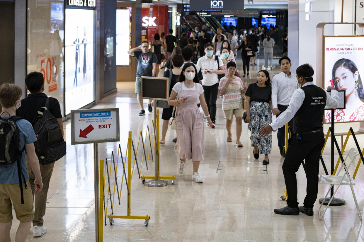 SINGAPORE, SINGAPORE - MARCH 31: A mall ambassador directs traffic through the barricade at a shopping mall on March 31, 2020 in Singapore. The Singapore government has introduced several safe distancing measures to curb the spread of COVID-19. (Photo by Ore Huiying/Getty Images)