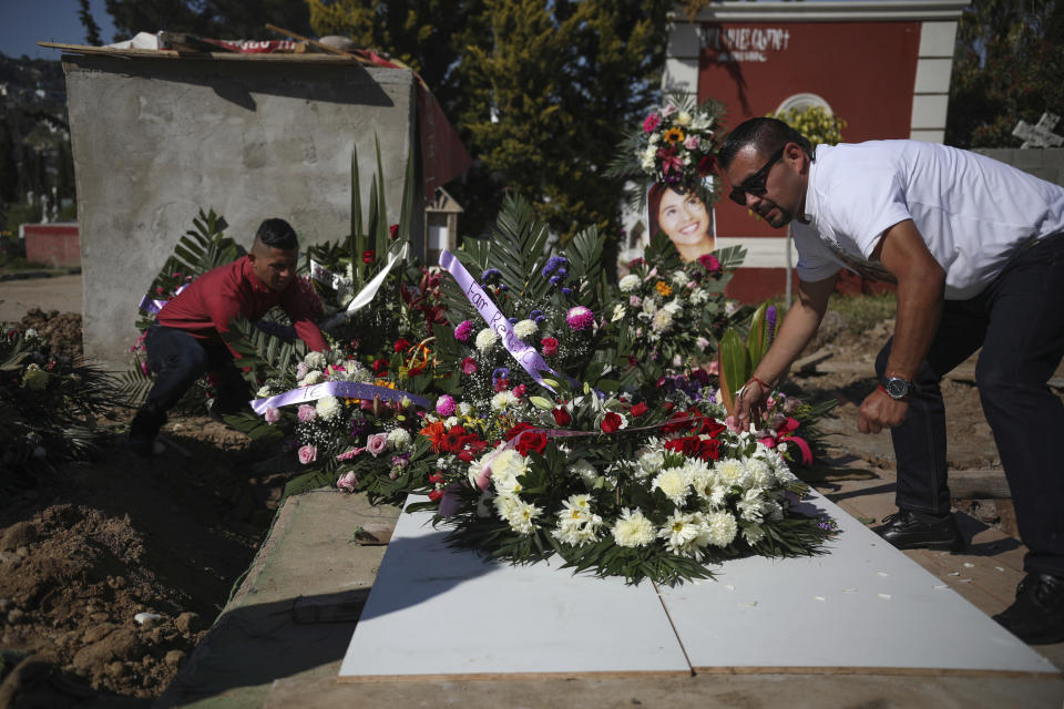 Juan, right, who has been arrested in connection with the disappearance and murder of Marbella Valdez, puts a floral arrangement on her grave, alongside her ex-boyfriend Jairo Solano, during her funeral at a cemetery in Tijuana, Mexico, Friday, Feb. 14, 2020. Juan, who sent her gifts and brought food for her friends, demanded police solve her case after the 20-year-old law student's body, beaten, bound and strangled, was found at a Tijuana garbage dump. Juan has insisted on his innocence. (AP Photo/Emilio Espejel)