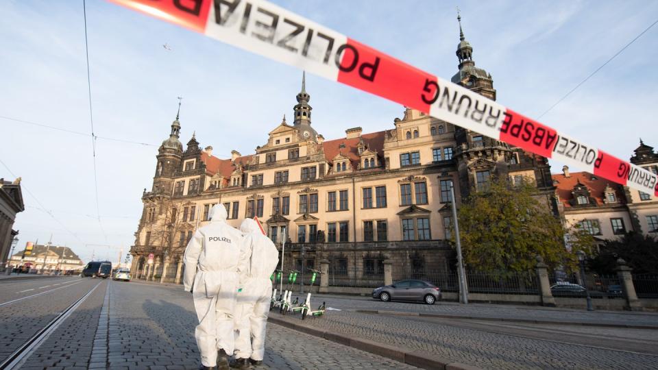 Zwei Mitarbeiter der Spurensicherung stehen im November 2019 vor dem Dresdner Residenzschloss mit dem Grünen Gewölbe hinter einem Absperrband.