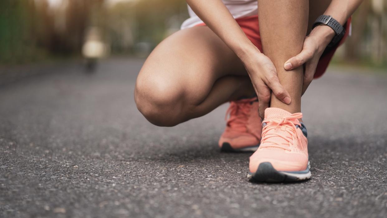  woman  runner holding ankle in pain 