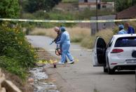 Police investigate the scene where an suspected gunman was shot by the police, after a deadly mass shooting near Pietermaritzburg