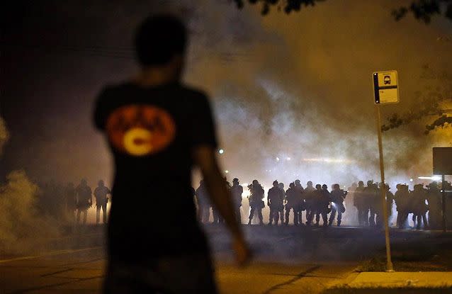 A man watches as police walk through a cloud of smoke during a clash with protesters. Source: AP Photo