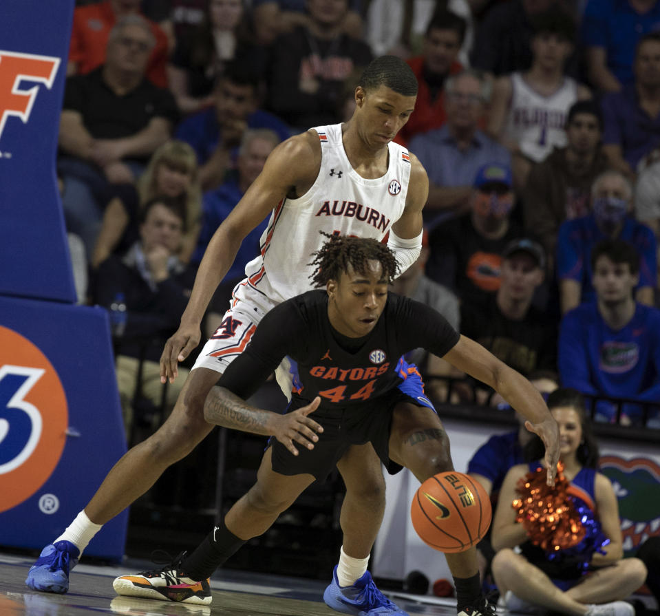 Florida guard Niels Lane (44) keeps the ball away from Auburn forward Jabari Smith (10) during the first half of an NCAA college basketball game Saturday, Feb. 19, 2022, in Gainesville, Fla. (AP Photo/Alan Youngblood)