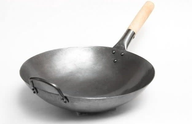 Cast iron wok with wooden handle on a white background