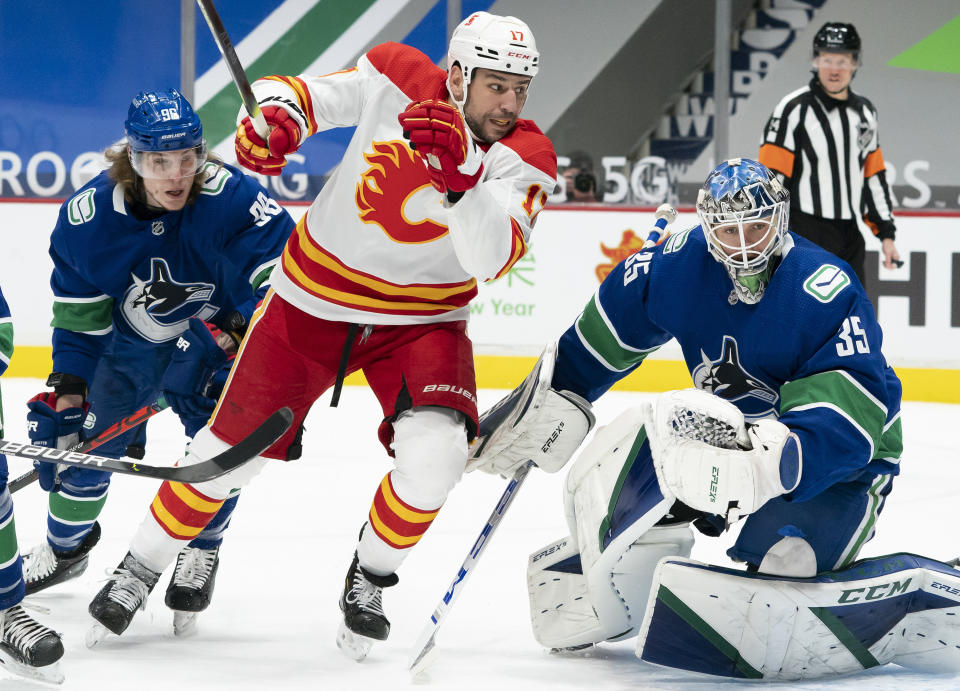 Vancouver Canucks center Adam Gaudette watches as Calgary Flames left wing Milan Lucic (17) tries to get a shot past Canucks goaltender Thatcher Demko (35) during the first period of an NHL hockey game Thursday, Feb. 11, 2021, in Vancouver, British Columbia. (Jonathan Hayward/The Canadian Press via AP)