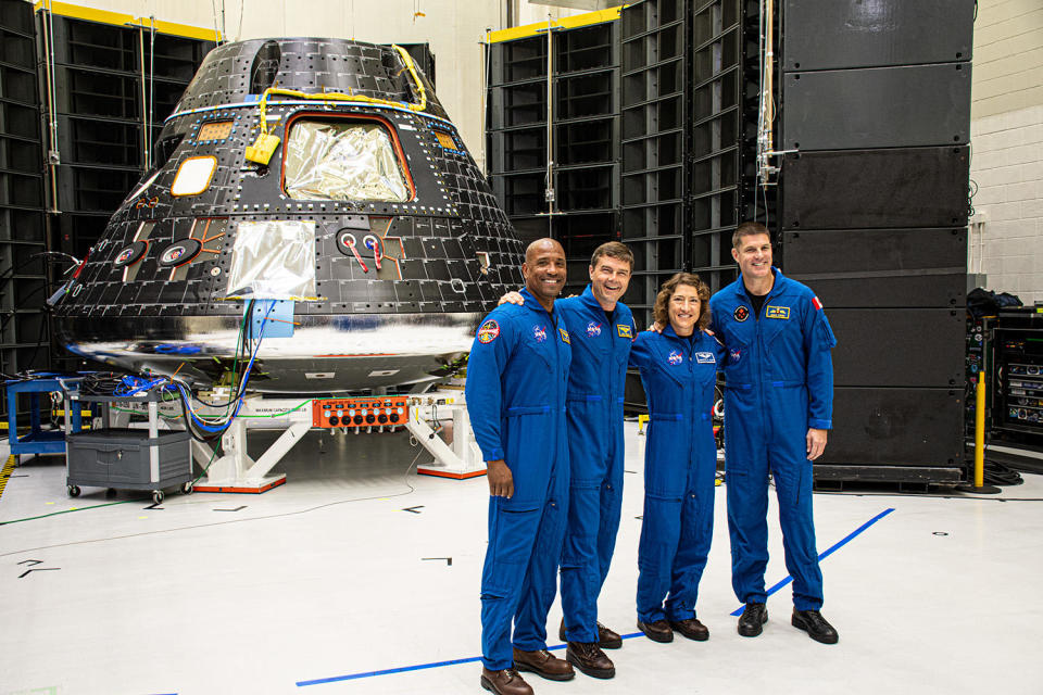 The Artemis 2 crew, standing in front of their Orion spacecraft, discusses their planned 2024 around-the-moon flight with reporters at the Kennedy Space Center. Left to right: Victor Glover, commander Reid Wiseman, Christina Koch and Canadian astronaut Jeremy Hansen. / Credit: William Harwood/CBS News