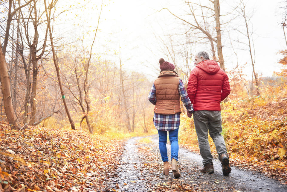 A woman and man walk along an outdoor trail in the autumn season