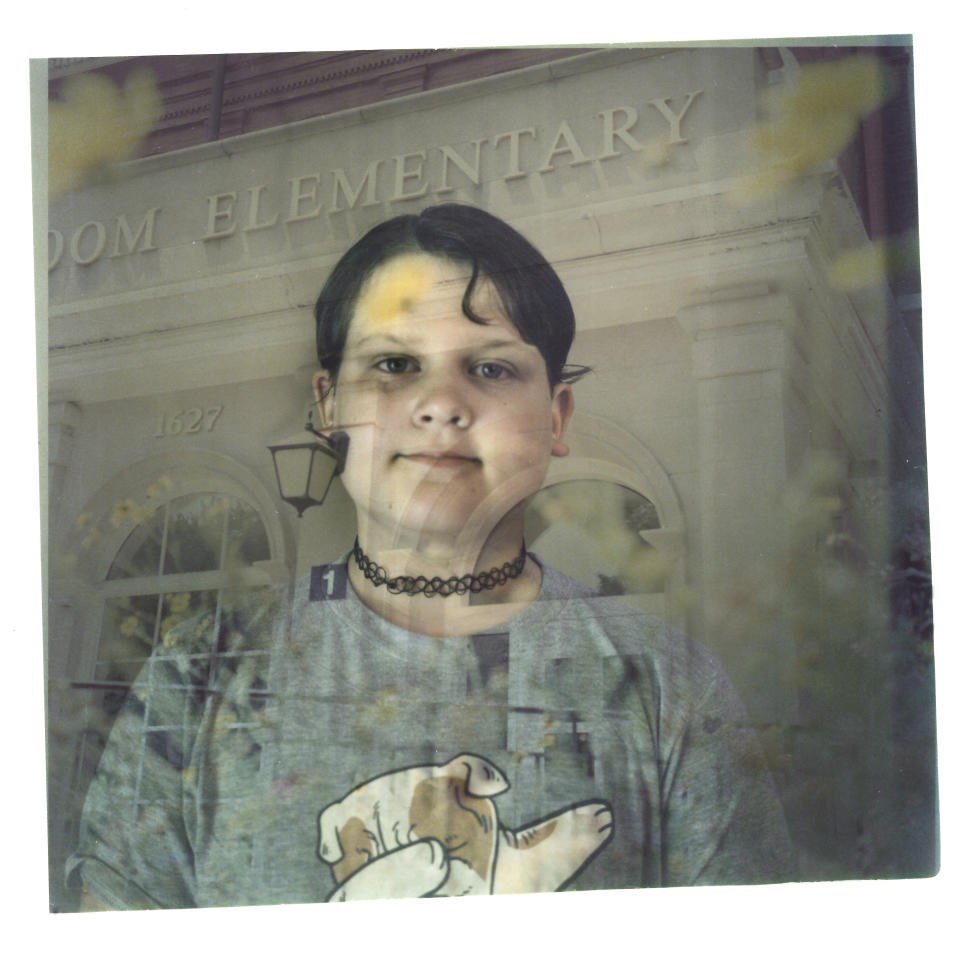 In this double exposure darkroom print made from two film negatives, a portrait of Sylvia Holm, 11, is layered with a photo of the elementary school she just graduated from in Louisville, Ky., Sunday, June 4, 2023. Holm's father was shot and survived one of the first school mass shootings to shatter the American consciousness a generation ago. When Sylvia started kindergarten, at the dinner table that fall, she announced that her class had learned a new drill. First her teacher locked the classroom door and turned off all the lights. Then she instructed the children to stay very quiet, "so the bad person wouldn't find them." When she turned seven, Sylvia heard her father's story for the first time during his speech on the steps of the federal courthouse in Louisville. She looked stricken, her eyes wide with fear. When Sylvia learned how close in age the children in Uvalde were to the friends around her, she started crying. Still, Sylvia says, if today's children are going to find ways to stop school shootings when they grow up, it was better to know. "When I was her age I would think, oh, the grownups are going to solve this. And here's she's telling us we're going to solve the problem," Kate says. But the expression on Sylvia's face remains stone serious. "Because the adults haven't done enough," she says. (AP Photo/David Goldman)