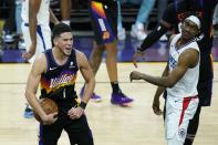 Phoenix Suns guard Devin Booker (1) celebrates near the end of the second half of Game 1 of the NBA basketball Western Conference finals as Los Angeles Clippers guard Terance Mann, right, looks on Sunday, June 20, 2021, in Phoenix. (AP Photo/Ross D. Franklin)