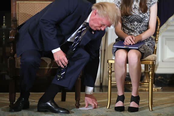 President Donald Trump picks up a pile of notes while in a listening session with gun violence survivors.