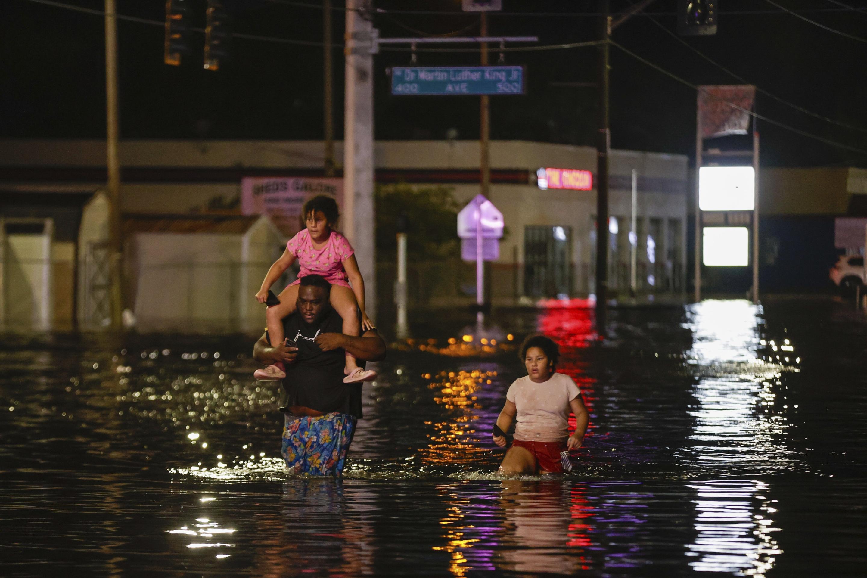 Jamir Lewis wades through the floodwaters after Hurricane Helene in Crystal River, Florida, on Friday with his two daughters, Nylah and Aria.