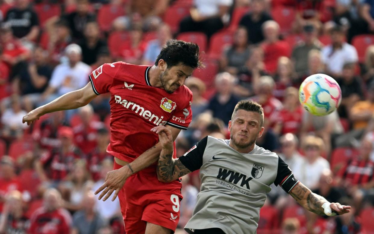 Leverkusen's Sardar Azmoun, left, and Augsburg's Jeffrey Gouweleeuw, right, fight for the ball during the Bundesliga soccer match