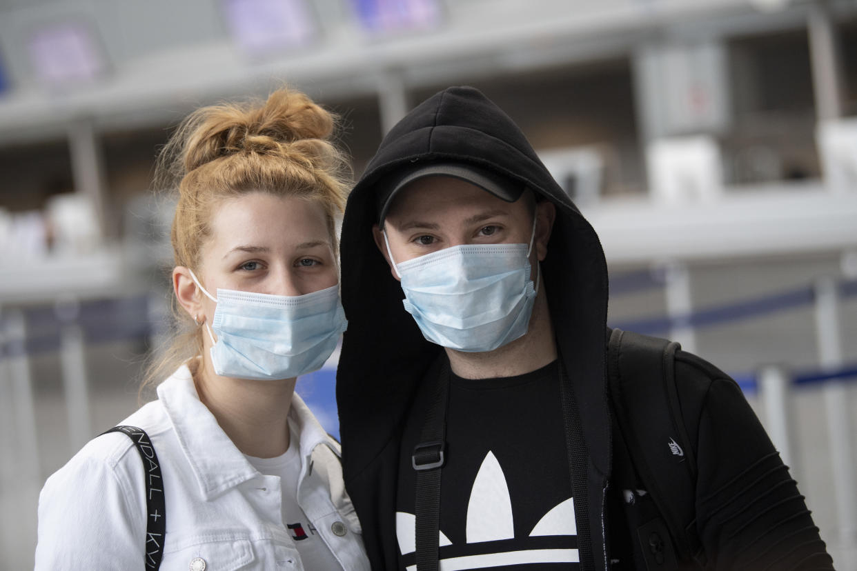 13 March 2020, Hessen, Frankfurt/Main: A young couple, who want to fly to Egypt, has equipped themselves with masks. As of Saturday, the USA has a ban on entry for Europeans. The aviation industry is also affected by the travel restrictions resulting from the Corona pandemic, Lufthansa alone has already cancelled more than 20,000 flights until April. Photo: Boris Roessler/dpa (Photo by Boris Roessler/picture alliance via Getty Images)