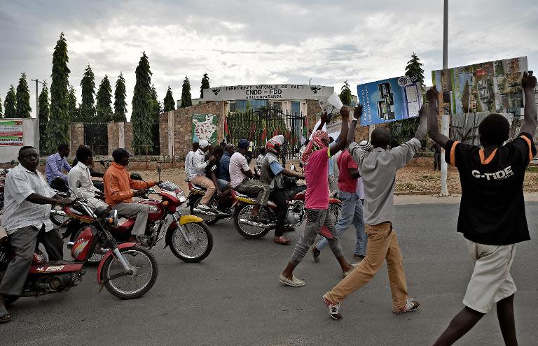 Protestors walk past the headquarters of the ruling party, the CNDD-FDD after burying the body of Zedi Feruzi, the head of the Union for Peace and Development opposition party on May 24, 2015 in Bujumbura