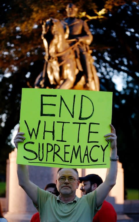 A protester stands in front of a statue of Robert E. Lee - Credit: AP