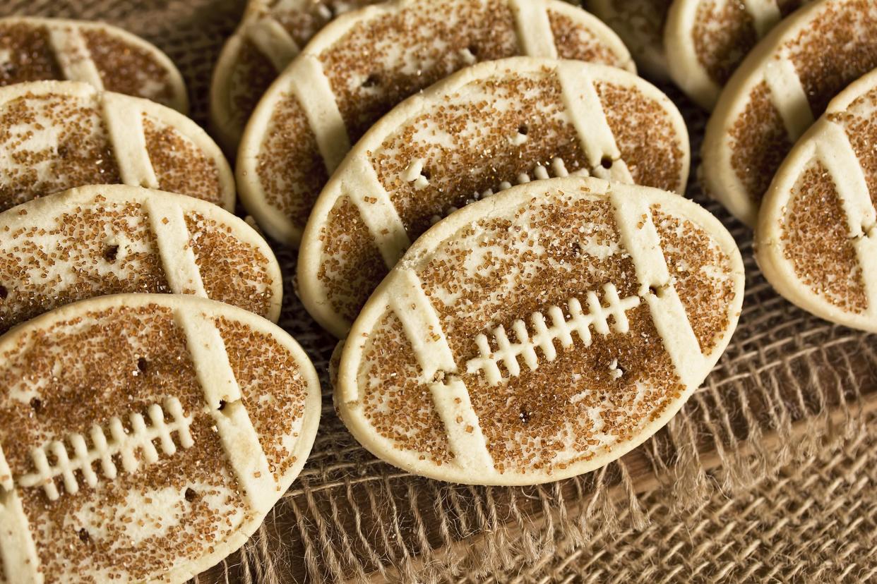Closeup of several of the best rolled sugar cookies shaped like footballs with brown sprinkle sugar on a natural napkin