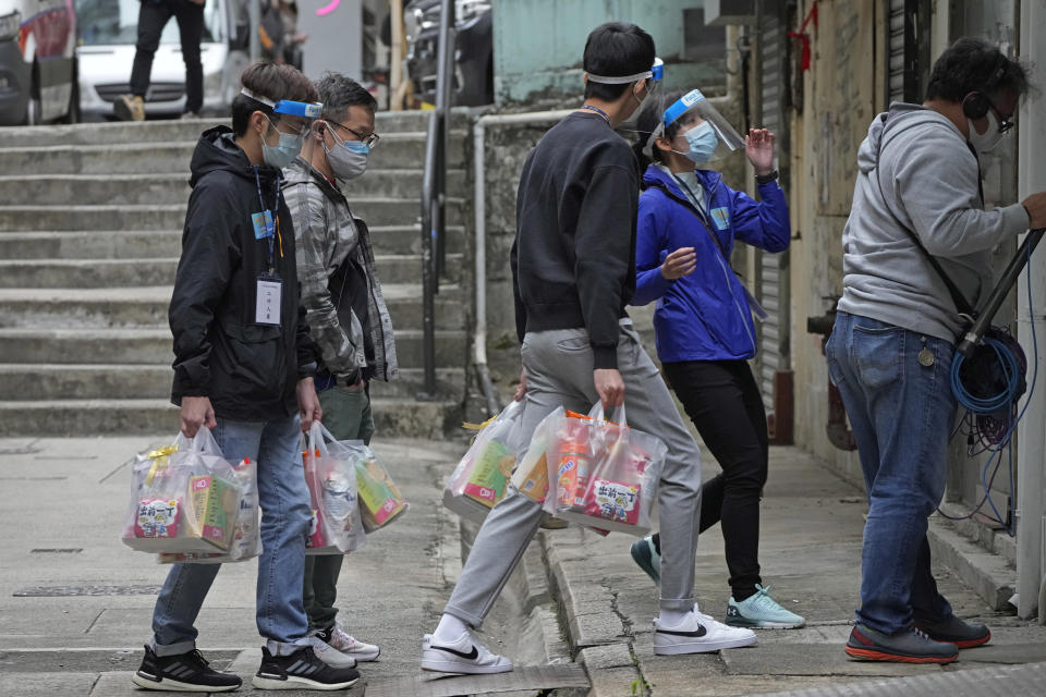 Workers deliver packages of coronavirus prevention materials to people during an anti-epidemic event in Hong Kong, Saturday, April 2, 2022. Hong Kong authorities on Saturday asked the entire population of more than 7.4 million people to voluntarily test themselves for COVID-19 at home for three days in a row starting next week. (AP Photo/Kin Cheung)
