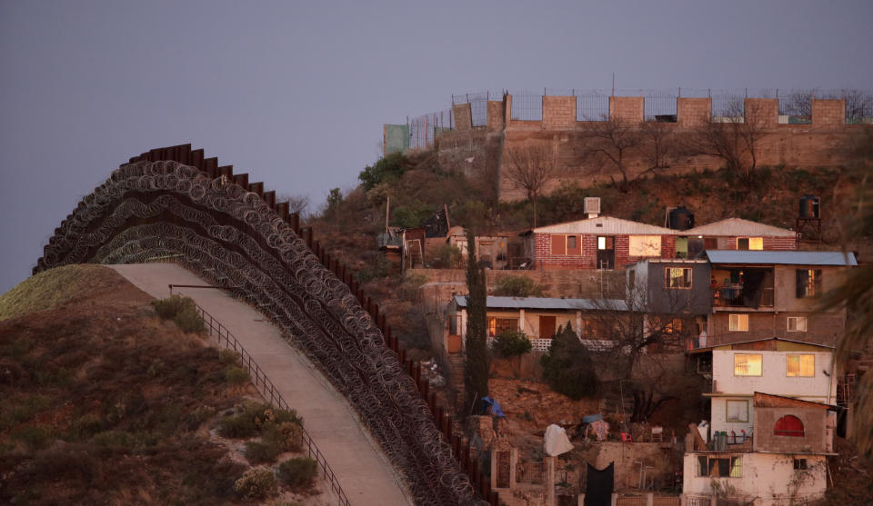 A razor-wire-covered border wall separates Nogalas, Mexico, at right, and Nogales, Ariz. at dusk Saturday, March 2, 2019. (AP Photo/Charlie Riedel)