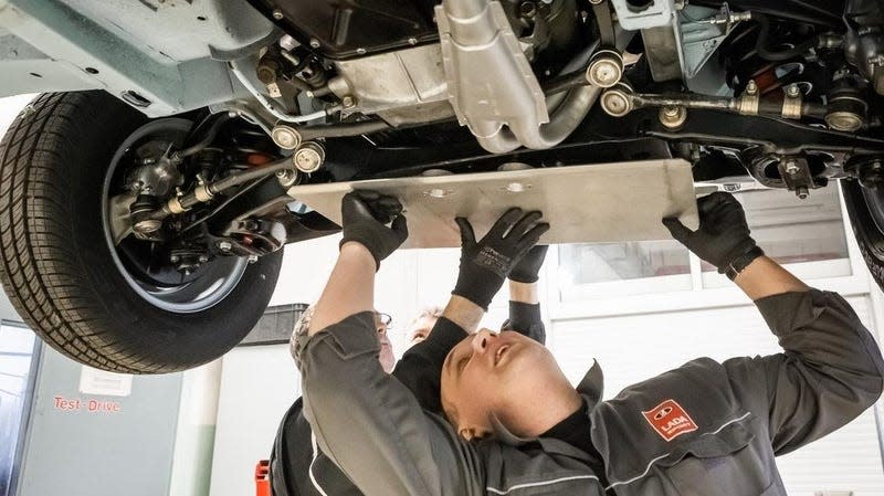 A person works beneath a car on a lift