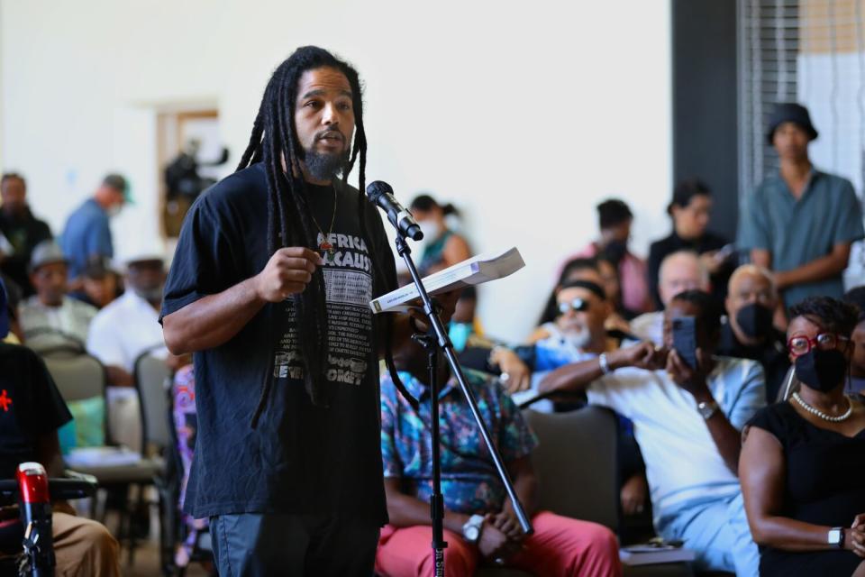 An audience member standing and speaking into a microphone as others listen.