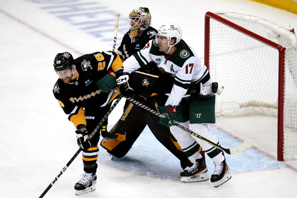 Minnesota Wild's Marcus Foligno (17) works against Pittsburgh Penguins' Jeff Petry (26) for position in front of Penguins goaltender Tristan Jarry during the first period of an NHL hockey game in Pittsburgh, Thursday, April 6, 2023. (AP Photo/Gene J. Puskar)