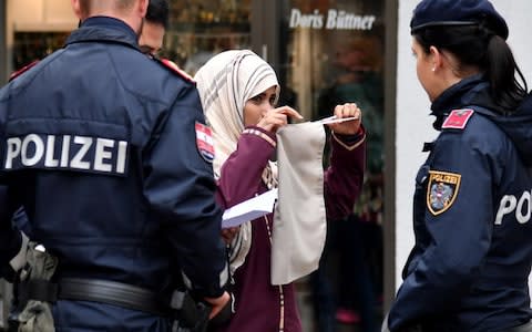 Police officers ask a woman to unveil her face in Zell am See, Austria - Credit: BARBARA GINDL/AFP/Getty Images