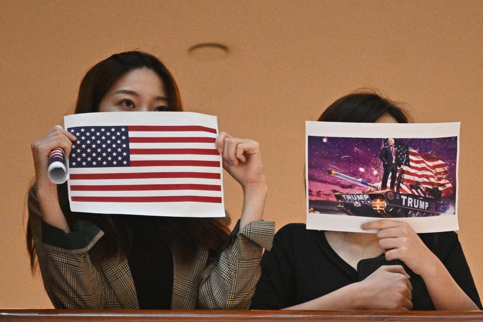 Two women hold up posters of the U.S. flag and a depiction of President Donald Trump, right, during a pro-democracy rally in a shopping mall in Hong Kong on May 28, 2020.