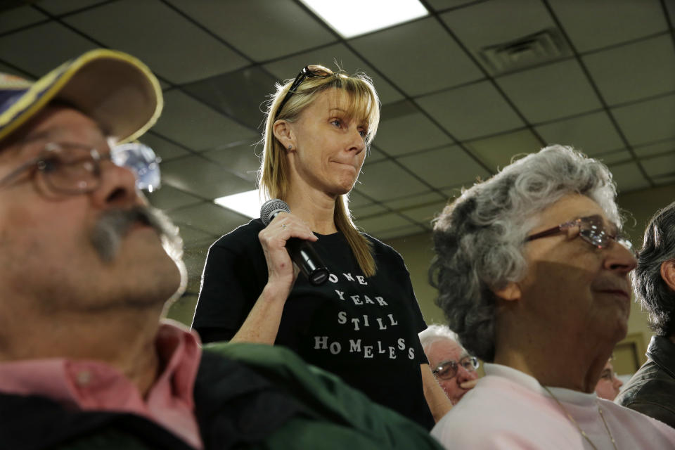 Debbie Fortier, of Brick, N.J., wears a shirt that says, one year still homeless, as she asks Gov. Chris Christie a question Thursday, Feb. 20, 2014, in Middletown, N.J., during a town hall meeting. Christie returned to Republican-controlled Monmouth County on Thursday for his first town hall since private emails revealed a political payback scandal in which his associates ordered traffic lanes closed, causing lengthy backups. But the scandal didn't come up. Instead, the 51-year-old Republican heard from residents who have not returned to their homes since the 2012 storm. (AP Photo/Mel Evans)