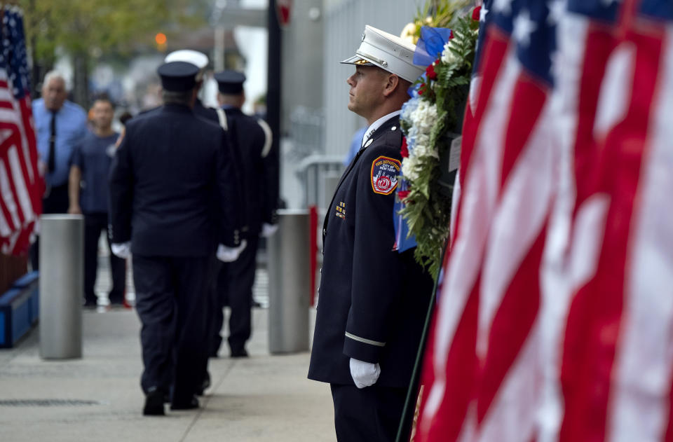 New York City firefighters take their positions in front of a memorial on the side of a firehouse adjacent to One World Trade Center and the 9/11 Memorial site during ceremonies commemorating the 18th anniversary of the 9/11 terrorist attacks in New York on Wednesday, Sept. 11, 2019. (AP Photo/Craig Ruttle)