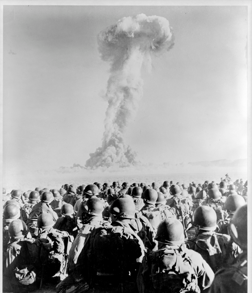 Members of the 11th Airborne Division kneel and watch a mushroom cloud stemming from an atomic bomb test at Frenchman’s Flat, Nevada Test Site, in November 1951. (Photo: Library of Congress)