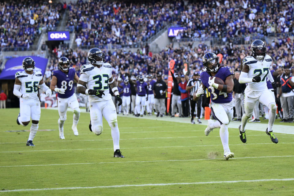 Baltimore Ravens running back Keaton Mitchell (34) runs from Seattle Seahawks safety Jamal Adams (33) and cornerback Riq Woolen (27) during a 40-yard touchdown run in the second half of an NFL football game, Sunday, Nov. 5, 2023, in Baltimore. (AP Photo/Nick Wass)