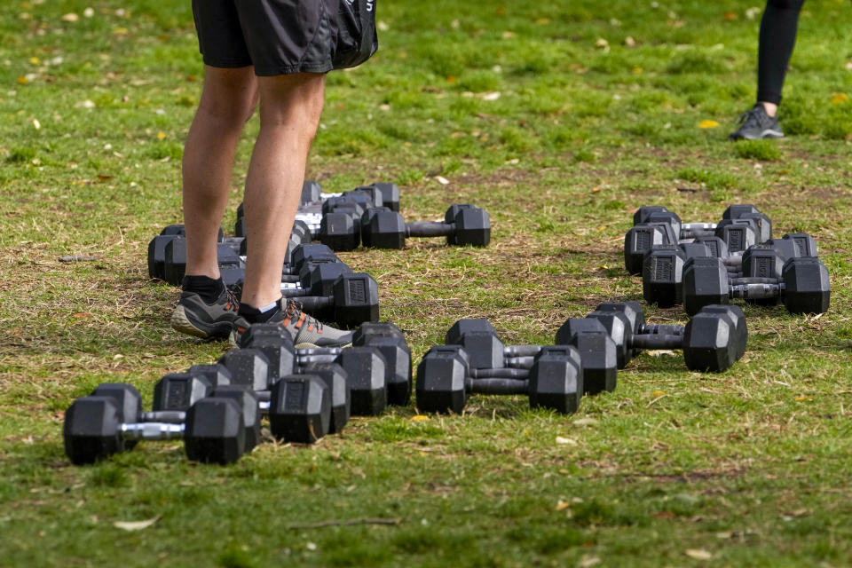 A client stands amongst a selection of weights in a park in the eastern suburbs of Sydney Tuesday, Sept. 14, 2021. Personal trainers have turned a waterfront park at Sydney’s Rushcutters Bay into an outdoor gym to get around pandemic lockdown restrictions. (AP Photo/Mark Baker)