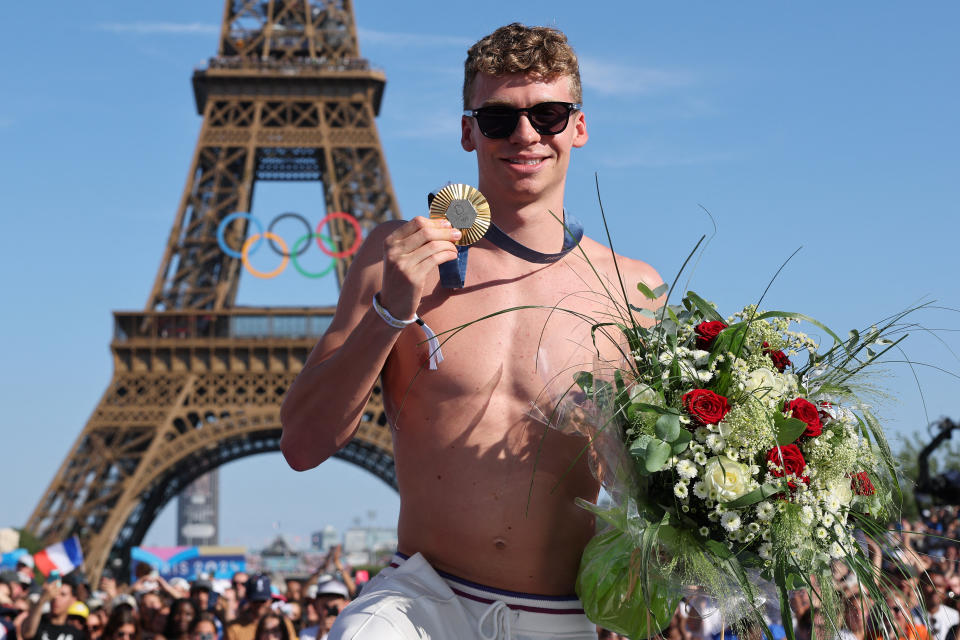 Leon Marchand poses with one of his four gold medals at the Champions Park at Trocadero. (Photo by JACK GUEZ/AFP via Getty Images)