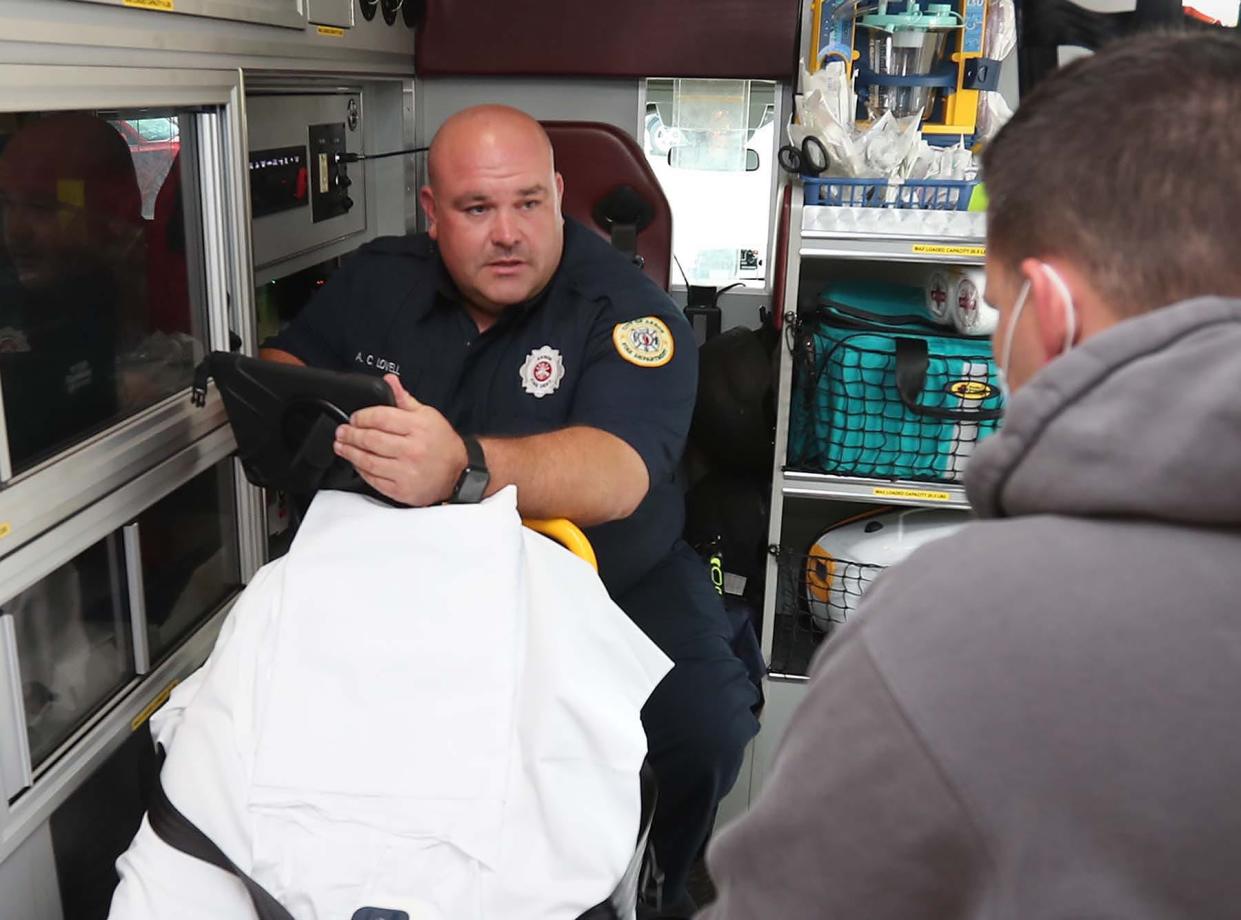 Firefighter/paramedic Adam Lovell works with the Akron Fire Department's new telehealth program during a September 2021 demonstration with firefighter/paramedic Dan Hilton portraying the patient.