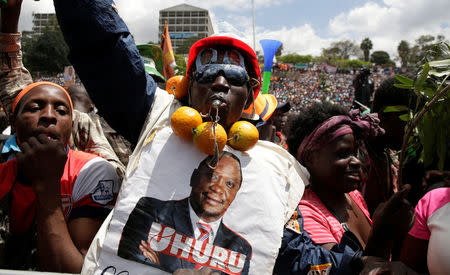 A supporter of Kenyan opposition National Super Alliance (NASA) coalition wears a poster decipting Kenya's President Uhuru Kenyatta at a rally endorsing Raila Odinga as the presidential candidate for the 2017 general elections at the Uhuru Park grounds, in Nairobi, Kenya, April 27, 2017. REUTERS/Thomas Mukoya