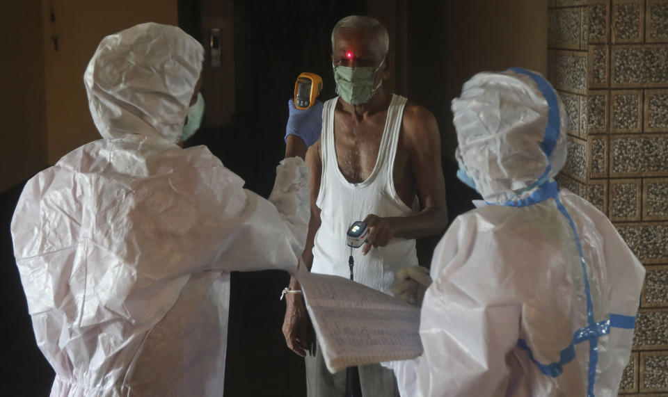 Health workers screen people for COVID-19 symptoms at a residential building in Dharavi , one of Asia's biggest slums, in Mumbai, India, Friday, Aug. 7, 2020. As India hit another grim milestone in the coronavirus pandemic on Friday, crossing 2 million cases and more than 41,000 deaths, community health volunteers went on strike complaining they were ill-equipped to respond to the wave of infection in rural areas.(AP Photo/Rafiq Maqbool)