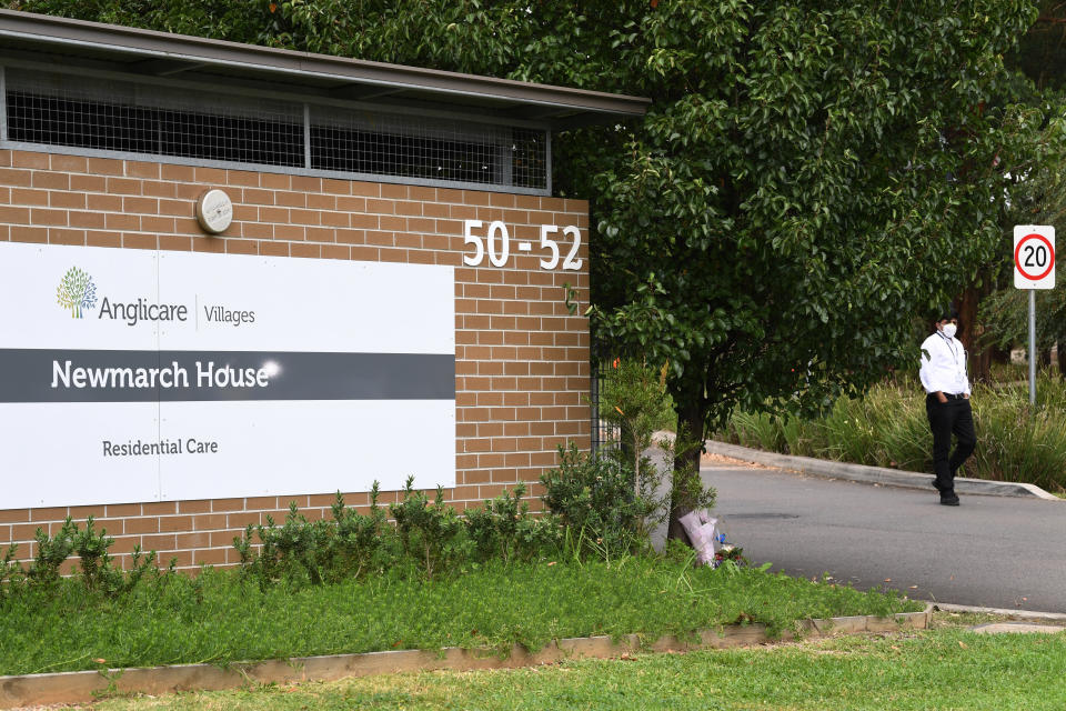 A security guard stands in the driveway as flowers are seen left at the entrance to Anglicare Newmarch House. Source: AAP