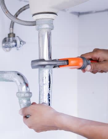 A person uses a tool to fix pipes. 