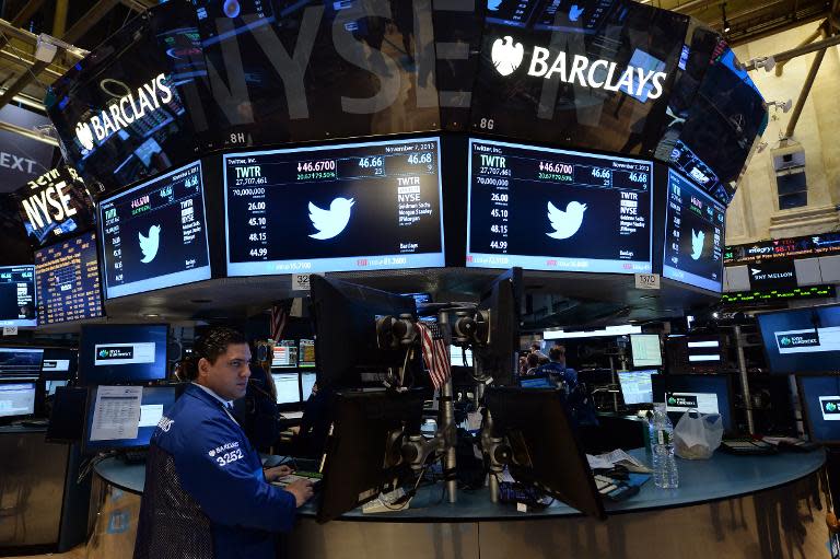 A stock trader works as Twitter logo and share price are displayed on screens on the trading floor of the New York Stock Exchange (NYSE) on November 7, 2013 in New York