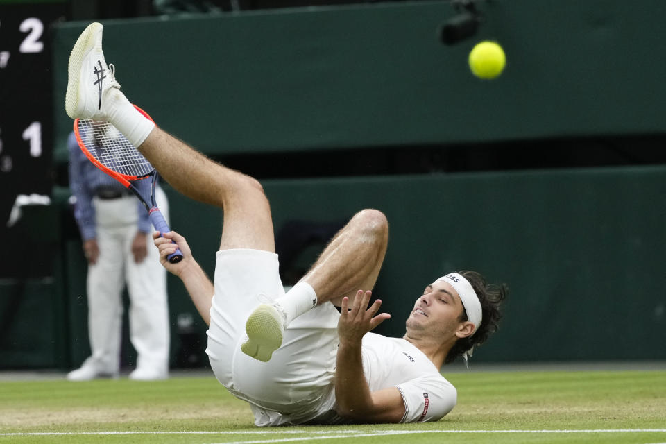 Taylor Fritz of the United States falls as he attempts to make a backhand return to Alexander Zverev of Germany during their fourth round match at the Wimbledon tennis championships in London, Monday, July 8, 2024. (AP Photo/Kirsty Wigglesworth)