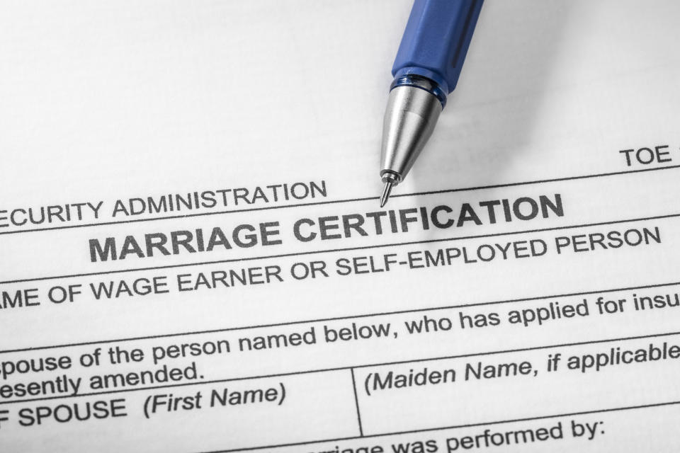 Close-up of a pen on a marriage certification form, showing spaces for names and signatures